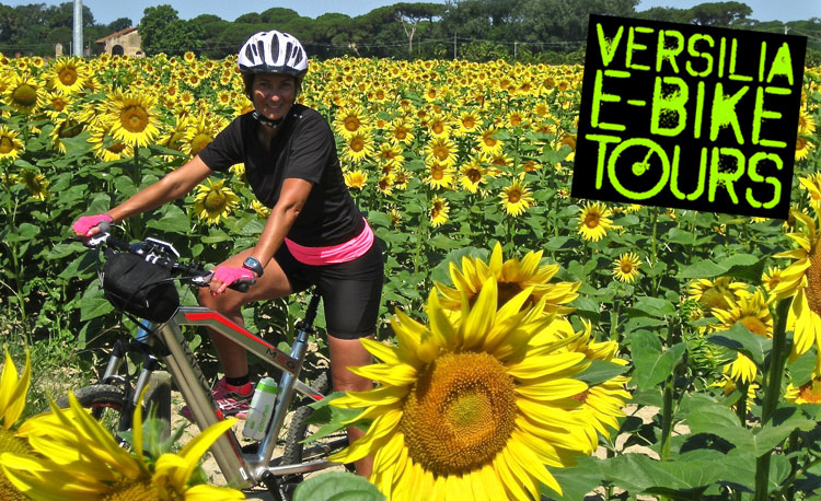 Una ciclista in sella a una ebike in un campo di girasole della Versilia
