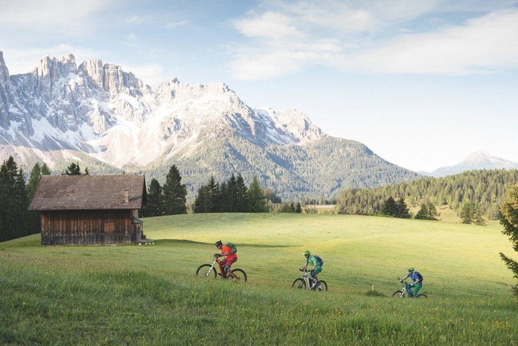Ciclisti pedalano in sella alle loro emtb e mountain bike elettriche lungo un sentiero tra le Dolomiti della Val Gardena. Hanno noleggiato le loro emtb.