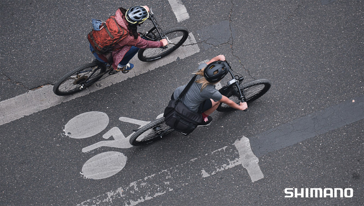 Una coppia pedala su una pista ciclabile in città in sella alle loro biciclette a pedalata assistita
