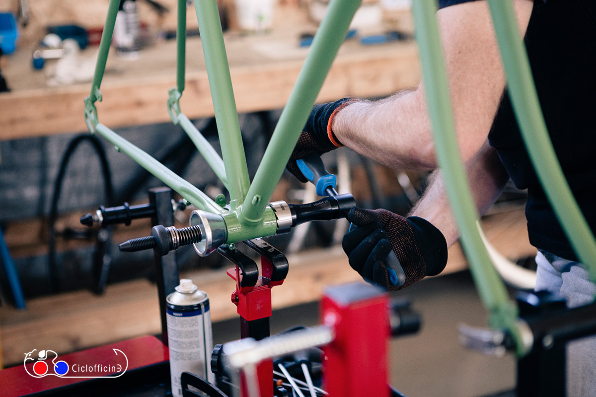 Un meccanico delle Ciclofficine srl di Bologna mentre opera su un telaio di bici