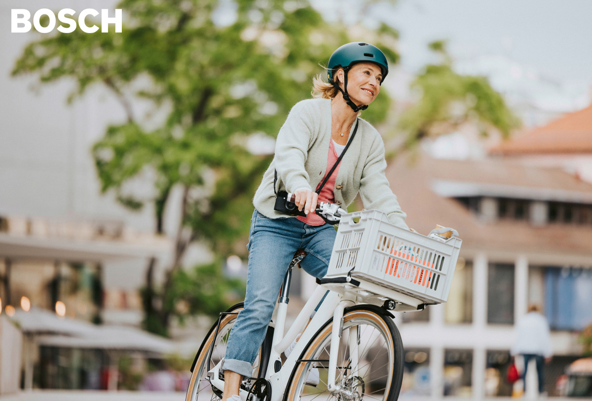 Donna pedala felice in sella a una bici elettrica equipaggiata Bosch Ebike Systems